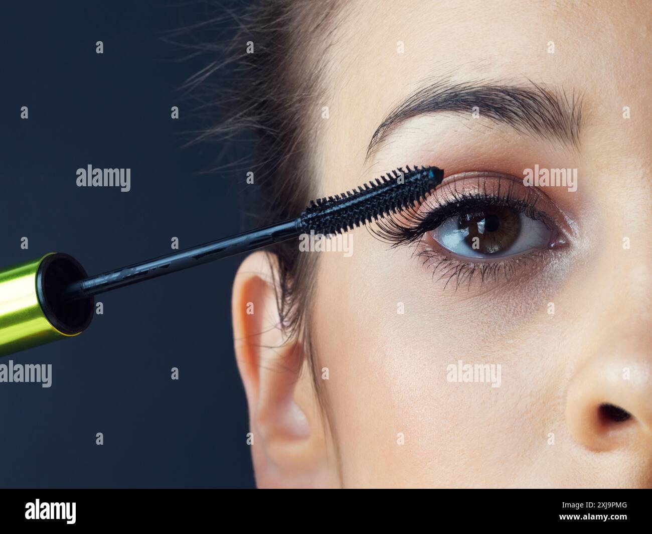 Donna, occhi e trucco con mascara per bellezza, volume o tonalità più scura in studio su uno sfondo scuro. Primo piano di una persona femminile o di un modello che presenta domanda Foto Stock