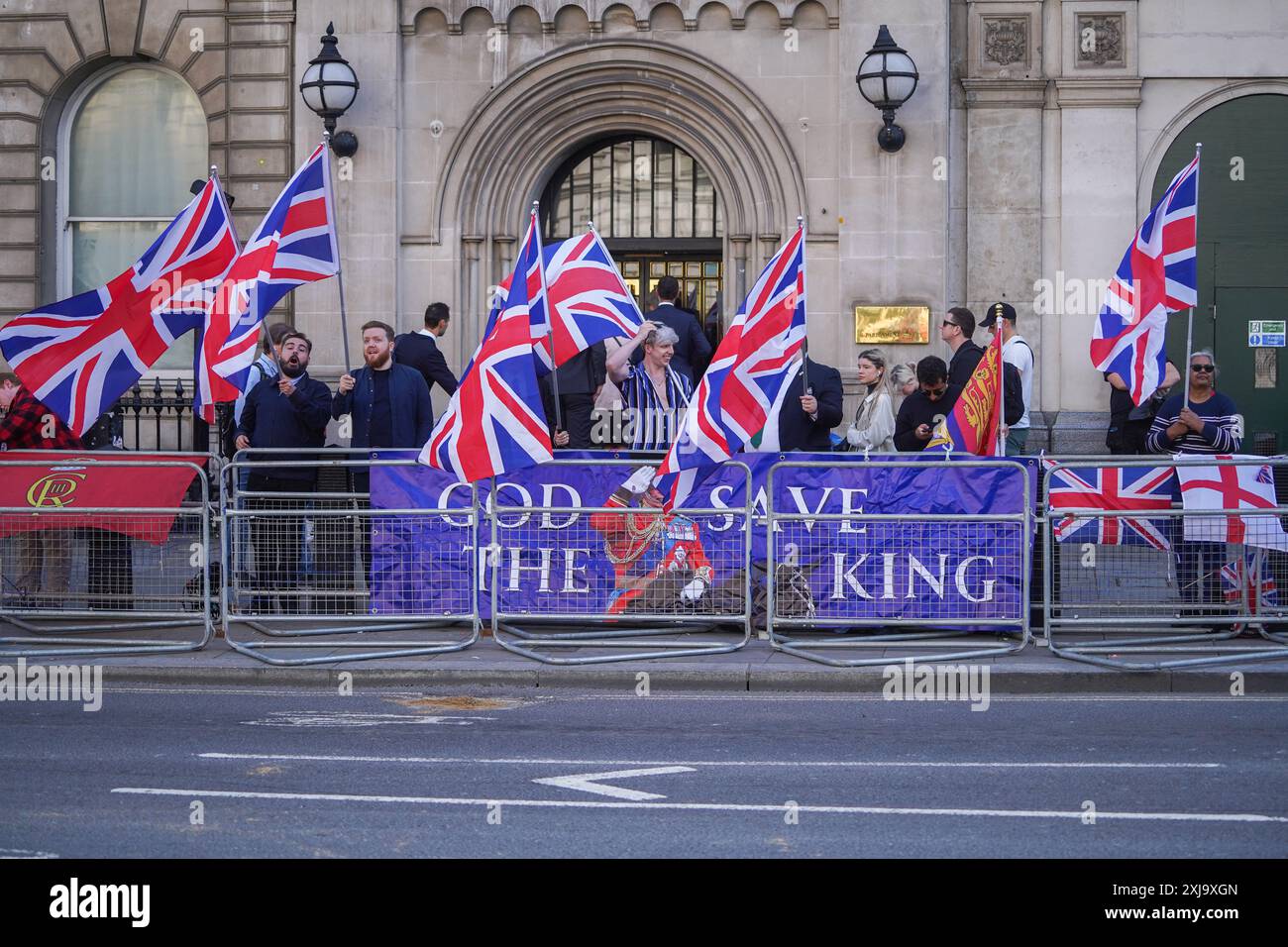 Westminster, Londra, Regno Unito. 17 luglio 2024 i sostenitori reali sventolano le bandiere Union Jack a Whitehall dietro uno striscione "God Save the King" prima dell'arrivo di re Carlo III per aprire la nuova sessione del parlamento. Il nuovo governo laburista introdurrà il suo programma legislativo nel discorso del re che delinea nuove leggi per dare priorità alla crescita economica per l'anno parlamentare. Crediti: Amer Ghazzal/Alamy Live News Foto Stock