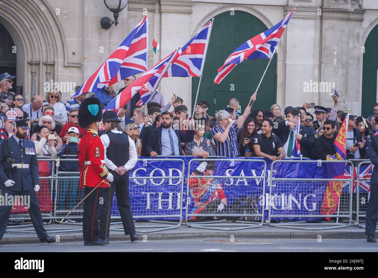 Westminster, Londra, Regno Unito. 17 luglio 2024 i sostenitori reali sventolano le bandiere Union Jack a Whitehall dietro uno striscione "God Save the King" prima dell'arrivo di re Carlo III per aprire la nuova sessione del parlamento. Il nuovo governo laburista introdurrà il suo programma legislativo nel discorso del re che delinea nuove leggi per dare priorità alla crescita economica per l'anno parlamentare. Crediti: Amer Ghazzal/Alamy Live News Foto Stock