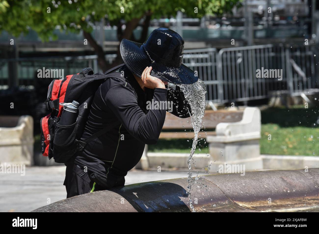 Un'onda di calore prolungata si avvicina al picco di Atene Un turista cerca di rinfrescarsi presso una fontana in Piazza Syntagma mentre un'onda di calore prolungata si avvicina al picco di Atene. Atene Grecia Copyright: XNicolasxKoutsokostasxNicolasxKoutsokostasx DSC 202407170096 Foto Stock