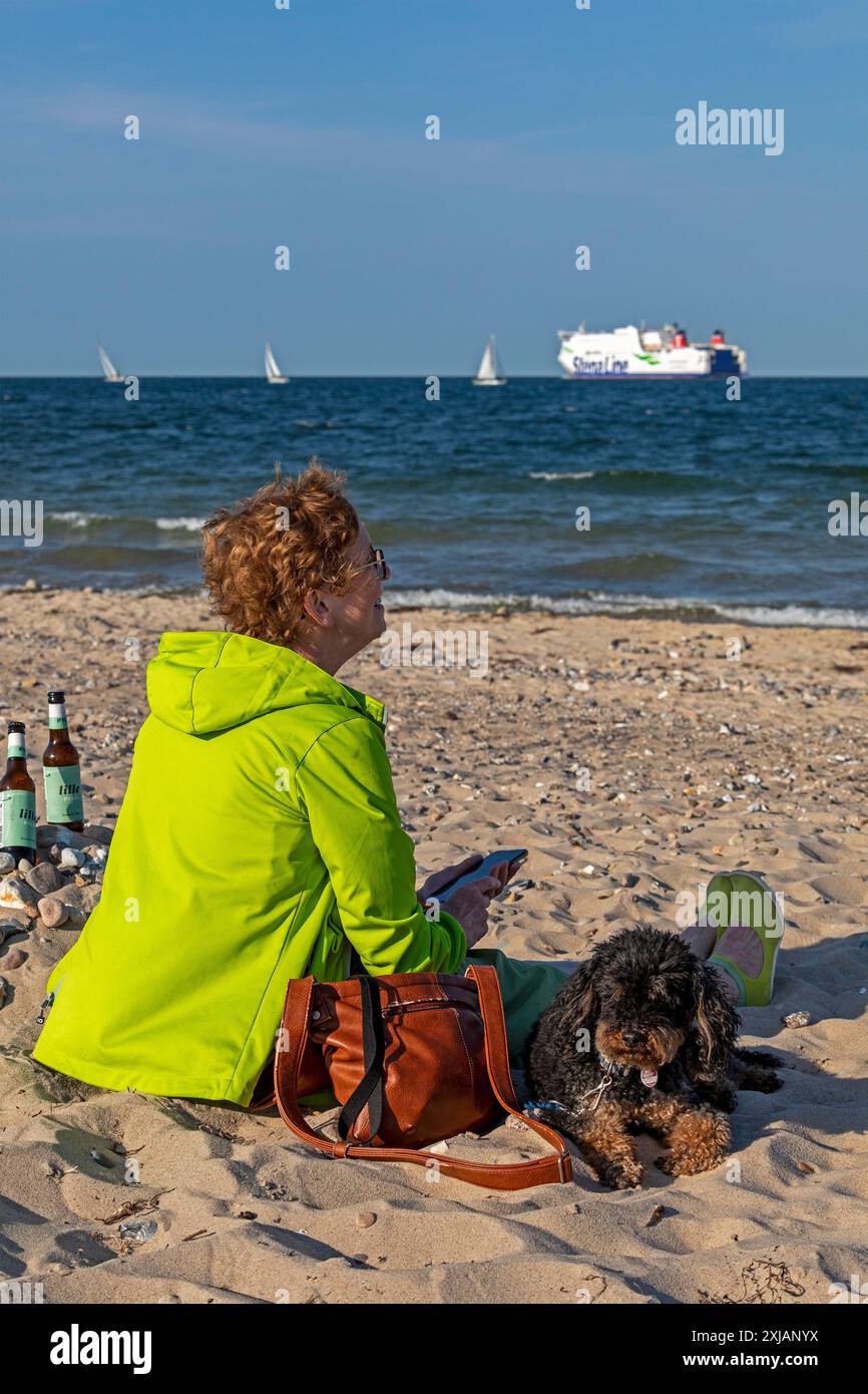 Donna anziana che guarda barche, barche a vela, traghetto, cane, bottiglie di birra, Kiel Week, Falckenstein Beach, Kiel Fjord, Kiel, Schleswig-Holstein, Germania Foto Stock