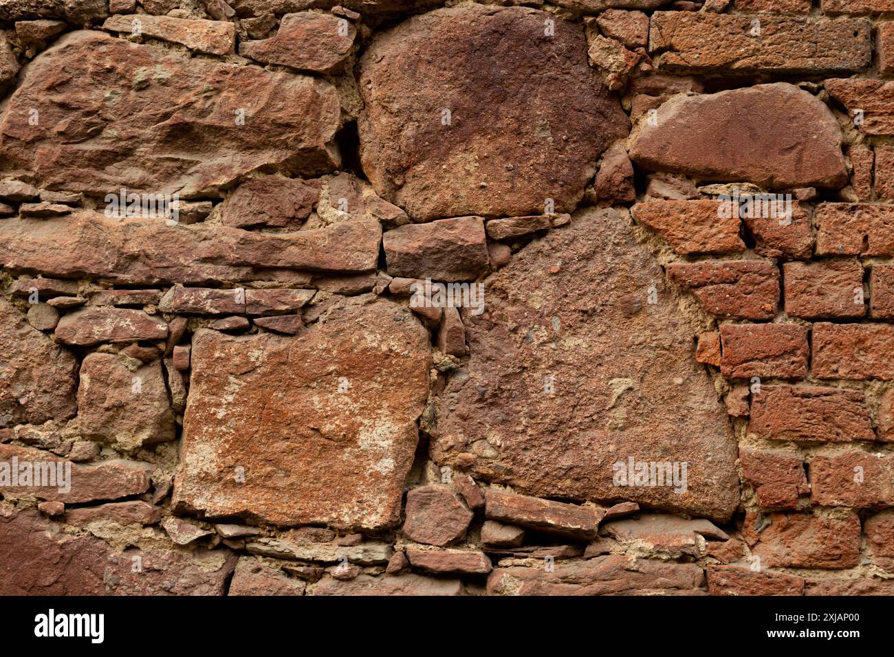 Primo piano. Vecchio muro rosso in pietra e mattoni di varie dimensioni. Sfondo o trama. Foto Stock