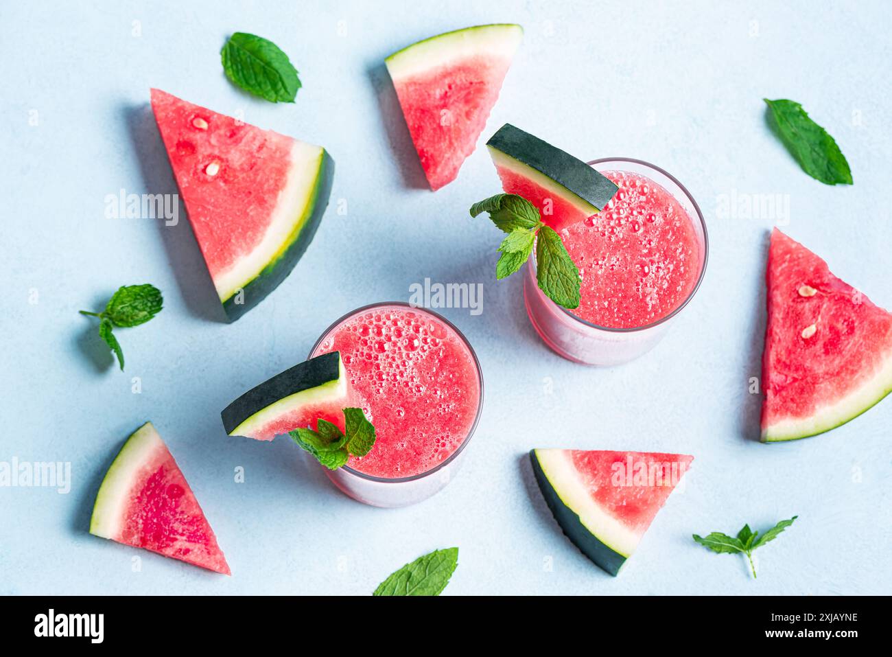 Succo di anguria fresco con foglie di menta in bicchieri su sfondo blu, vista dall'alto. Dolce frullato estivo, cocktail disintossicante, bevanda sana biologica. Foto Stock