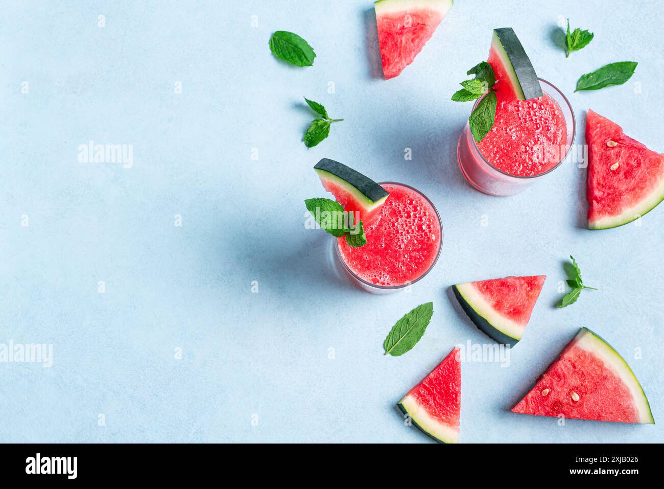 Succo di anguria fresco con menta in bicchieri su sfondo blu, vista dall'alto, spazio per copiare. Dolce frullato estivo, cocktail disintossicante, cibo sano biologico. Foto Stock