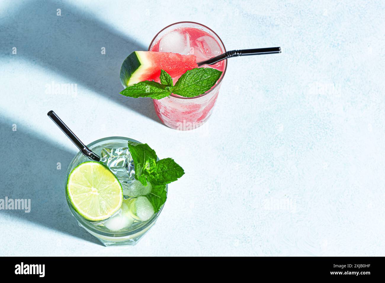 Cocktail estivi alla moda con anguria, lime, menta e ghiaccio su sfondo blu, vista dall'alto, spazio fotocopie. Cocktail party estivo, concetto di bar sulla spiaggia. Foto Stock