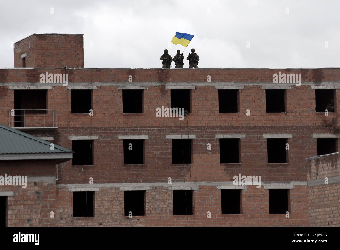 I soldati tengono la bandiera dell'Ucraina in cima all'edificio. liberazione dei territori. Guerra in Ucraina Foto Stock
