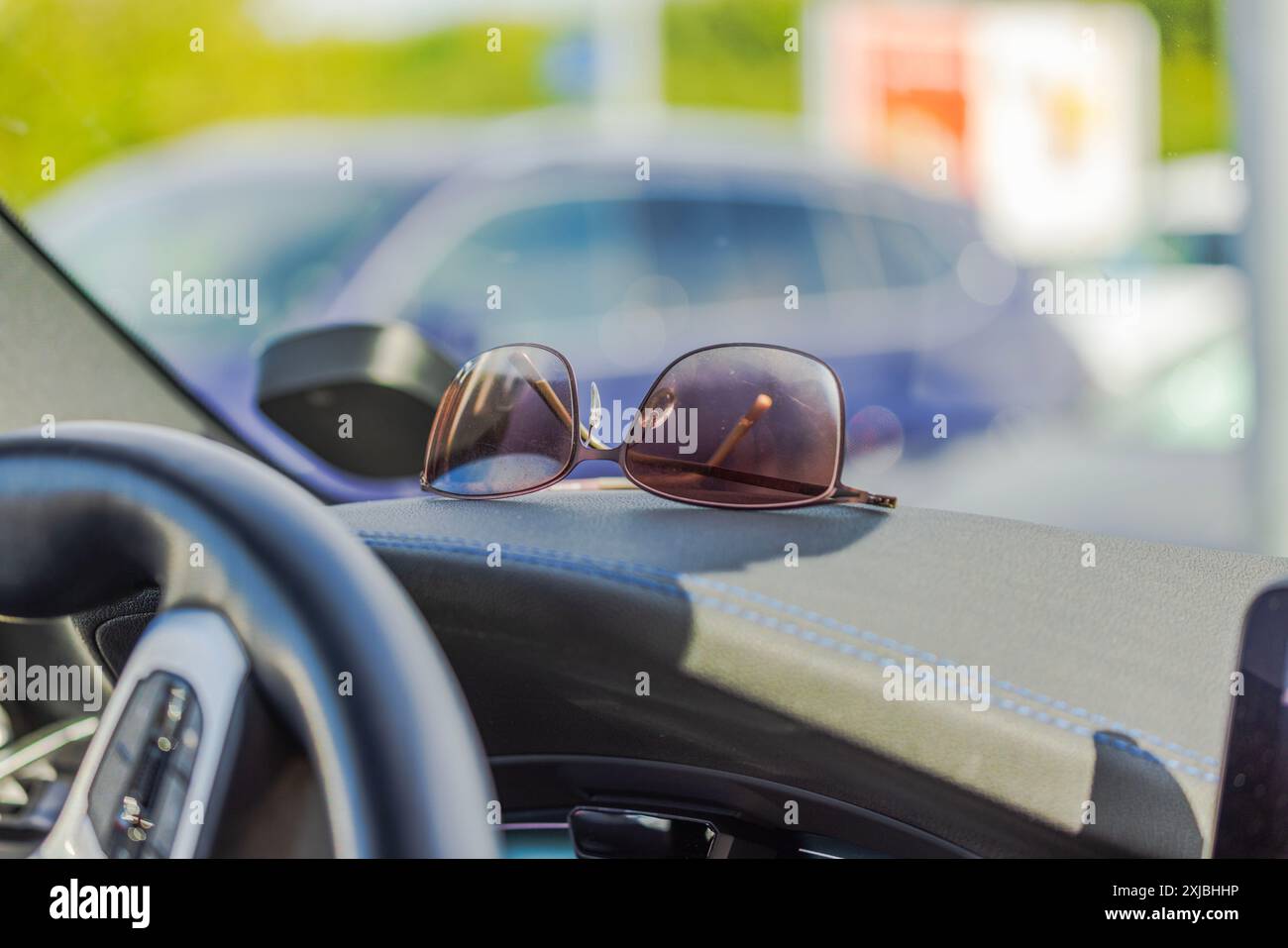 Vista ravvicinata degli occhiali da sole appoggiati sul cruscotto sul lato conducente dell'auto. Foto Stock