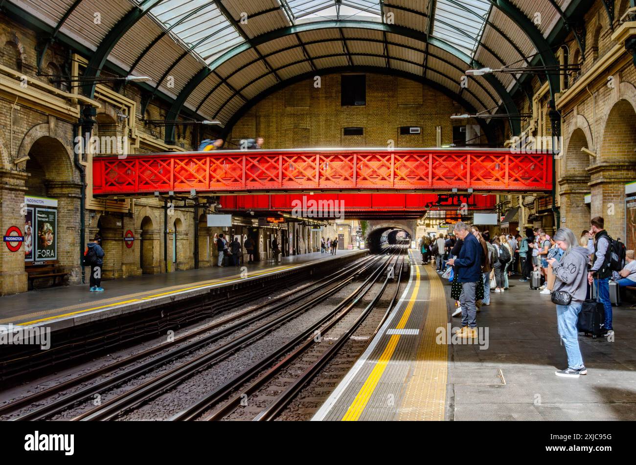 I passeggeri attendono un treno sul binario della stazione della metropolitana di Paddington London Foto Stock