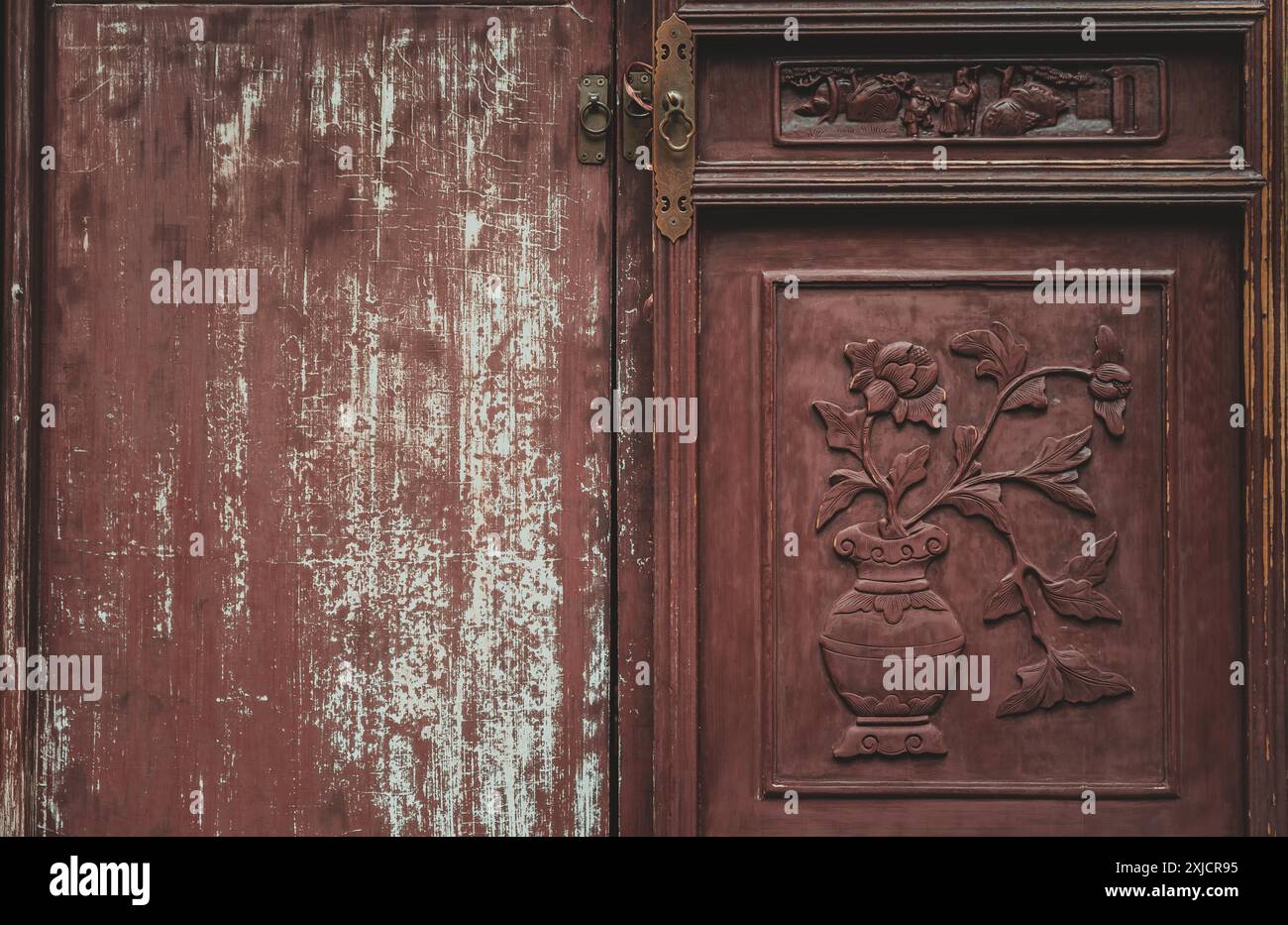 Un primo piano di una porta in legno marrone rossastro con intricate incisioni di fiori e foglie. La porta è divisa in due pannelli, con il lato destro Foto Stock