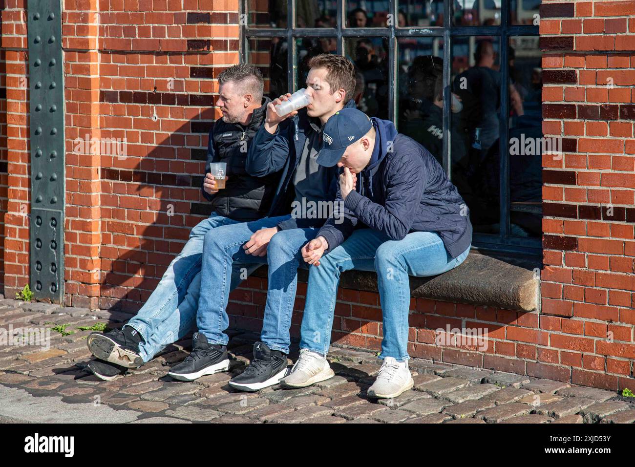 Persone che gustano bevande fuori Fischauktionshalle la domenica mattina nel quartiere Altona di Amburgo, Germania Foto Stock