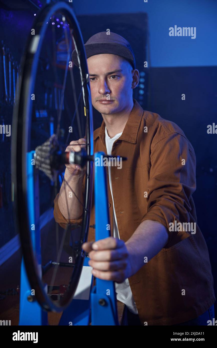 Il tecnico lavora la ruota della bicicletta controllando il corretto allineamento del cerchione Foto Stock