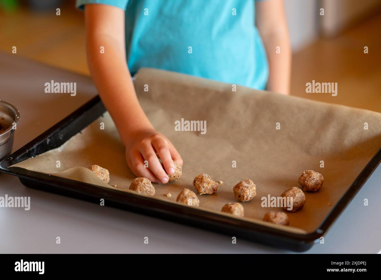 Le mani dei bambini preparano biscotti alle noci e li mettono su una teglia da forno Foto Stock