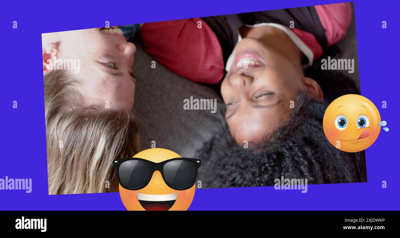 Immagine di varie emoji che si muovono su due ragazze adolescenti felici e diverse sdraiate sulla schiena che parlano Foto Stock