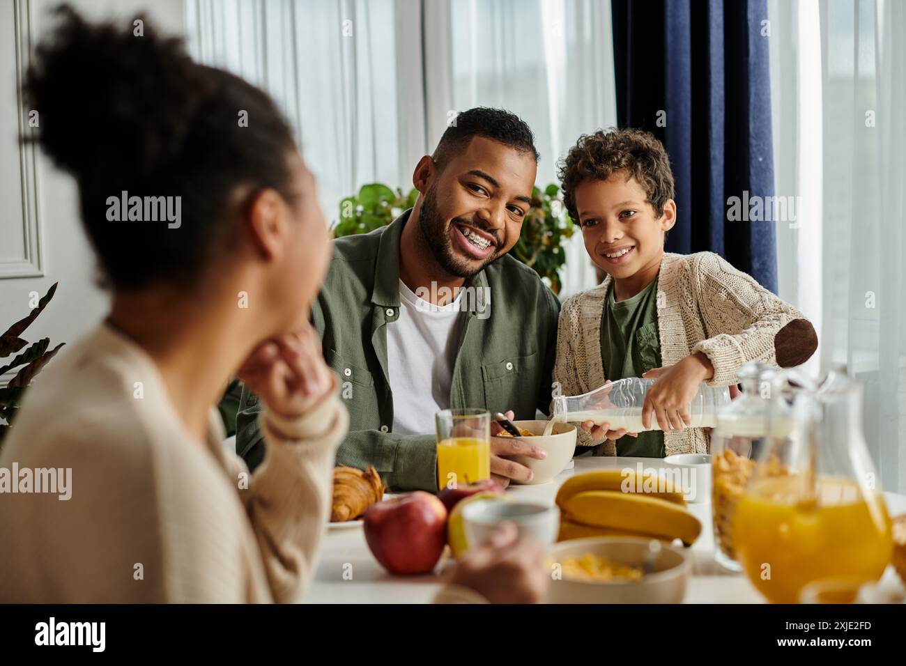 Famiglia afroamericana affiatata che condivide cibo e conversazione a tavola. Foto Stock