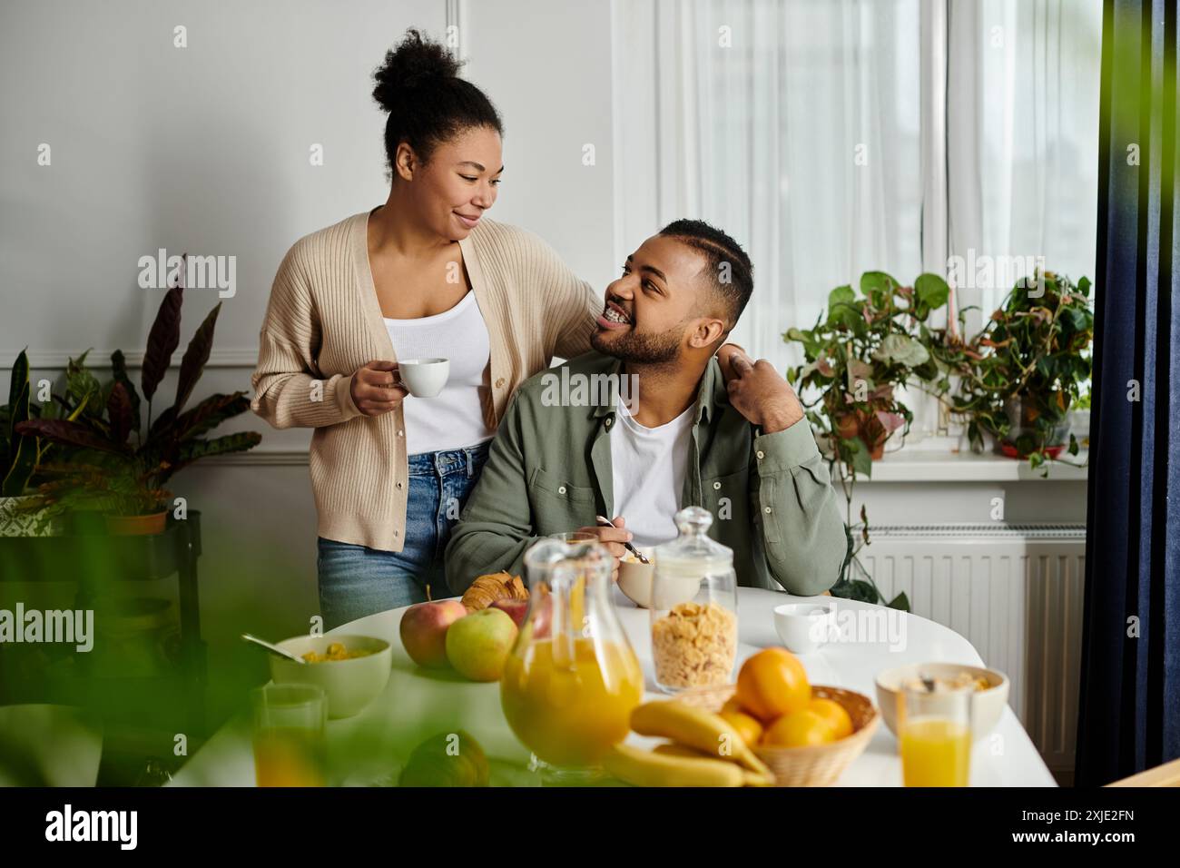 Un uomo e una donna si siedono a un tavolo con della frutta, godendosi un momento insieme. Foto Stock