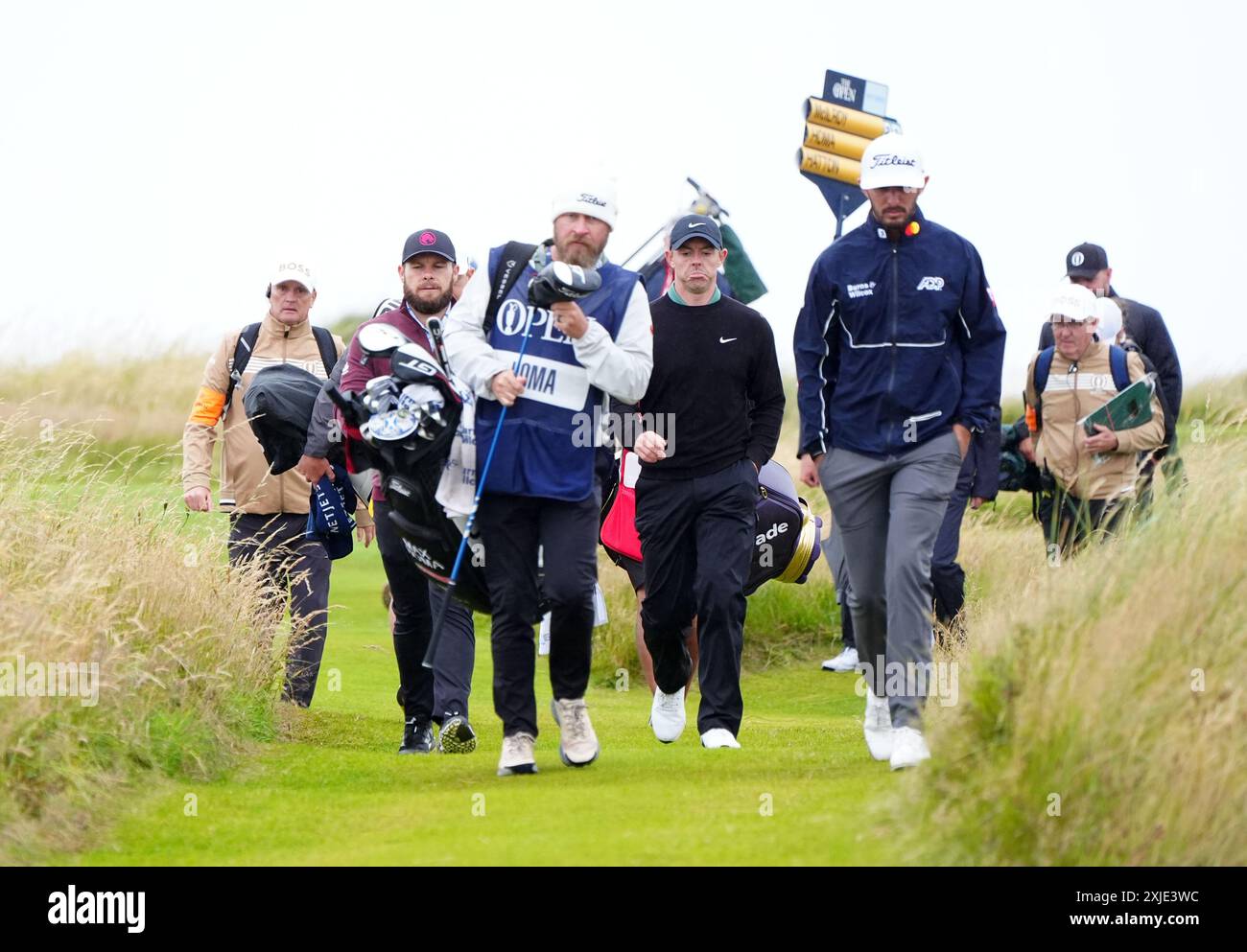 Rory McIlroy dell'Irlanda del Nord, Max Homa degli Stati Uniti e Tyrrell Hatton dell'Inghilterra escono dal quarto tee durante il primo giorno dell'Open al Royal Troon, South Ayrshire, Scozia. Data foto: Giovedì 18 luglio 2024. Foto Stock