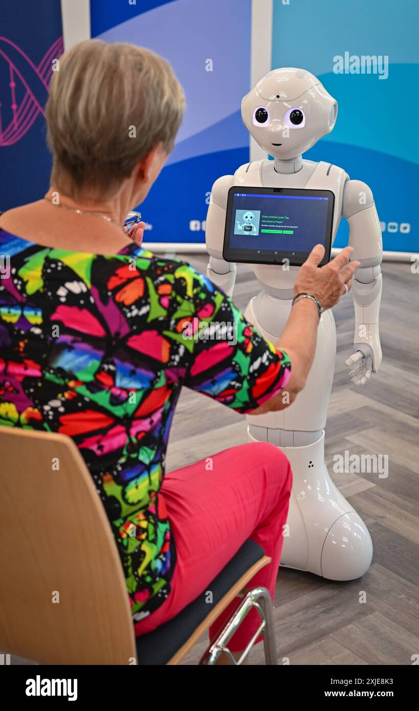 Cottbus, Germania. 18 luglio 2024. Un'interazione in tempo reale tra un paziente simulato e un robot può essere vista durante un evento stampa presso il Carl-Thiem-Klinikum Cottbus. Attualmente è in corso uno studio pilota presso la Brandenburg University of Technology Cottbus-Senftenberg (BTU) per studiare gli effetti delle modalità di interazione di un robot sociale (Pepper) sull'impegno e sulla percezione dei soggetti sottoposti a test in situazioni di assistenza tipiche. Crediti: Patrick Pleul/dpa/Alamy Live News Foto Stock