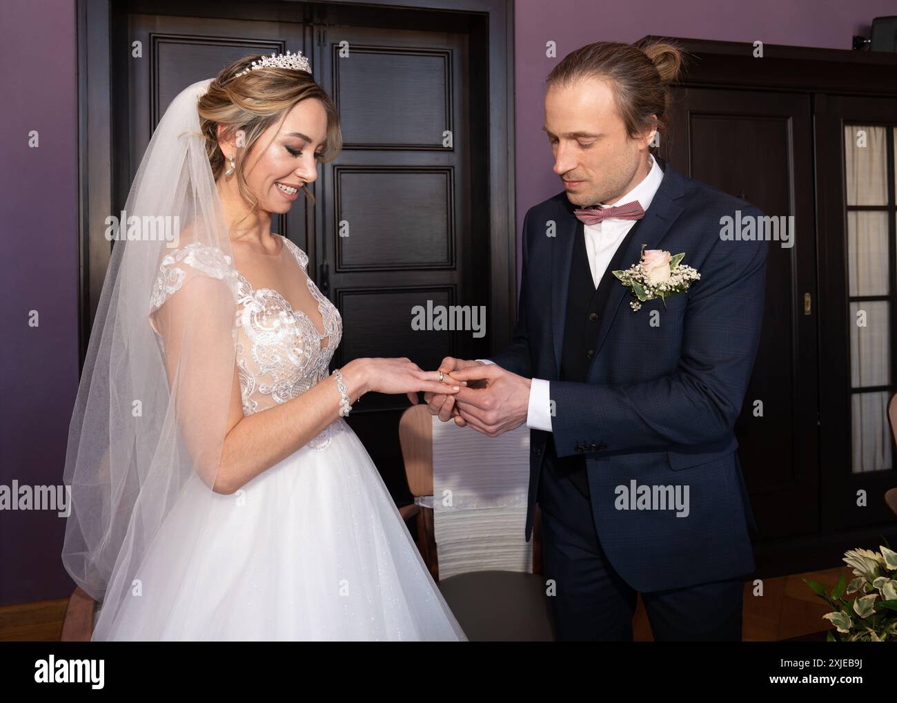 Matrimonio. Giovane sposa e sposo con abito da sposa bianco e abito blu. Anelli di matrimonio e di fidanzamento. Un paio di sposi novelli. Pegno di fedeltà e lo Foto Stock