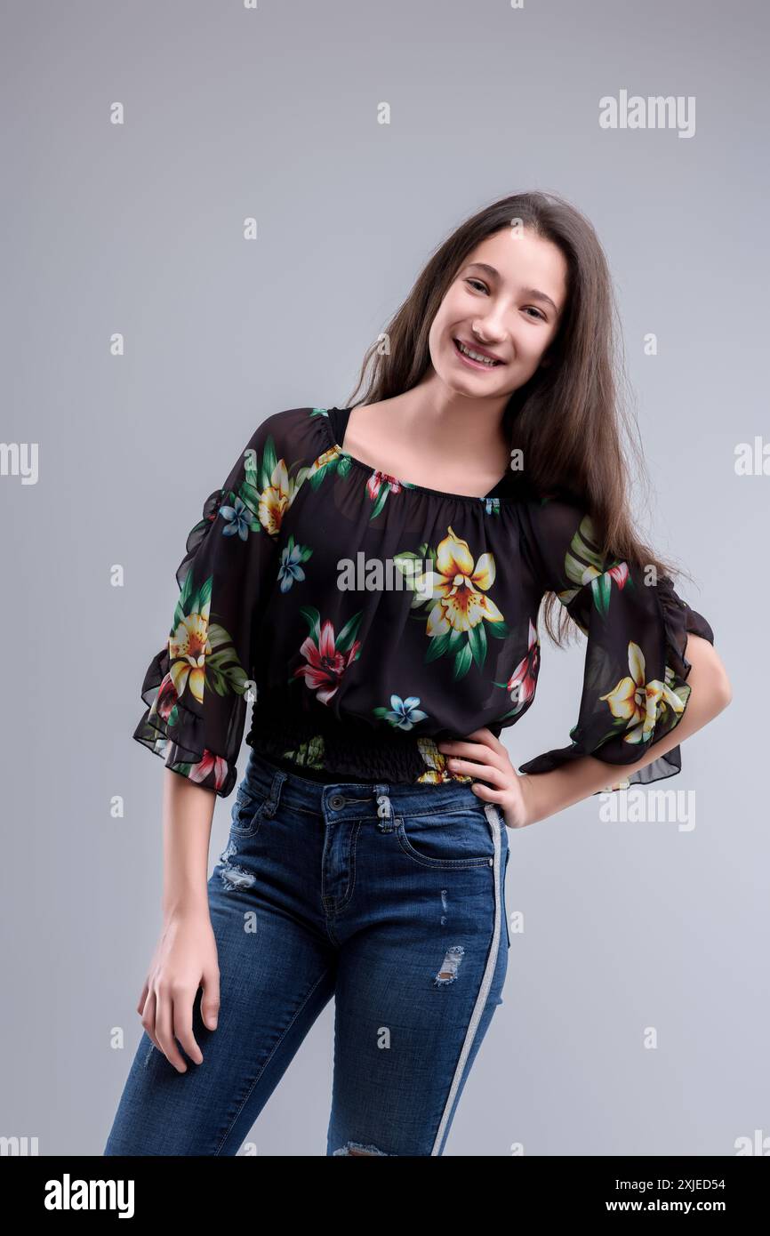 Una giovane donna sicura di sé con un outfit elegante si posa felicemente, mostrando femminilità moderna e vivacità giovanile Foto Stock