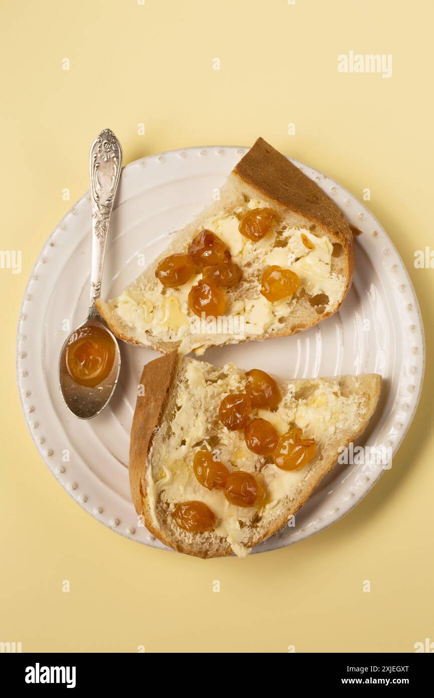 Dessert con pane fatto in casa, burro e marmellata di ciliegie gialle su sfondo beige, vista dall'alto Foto Stock