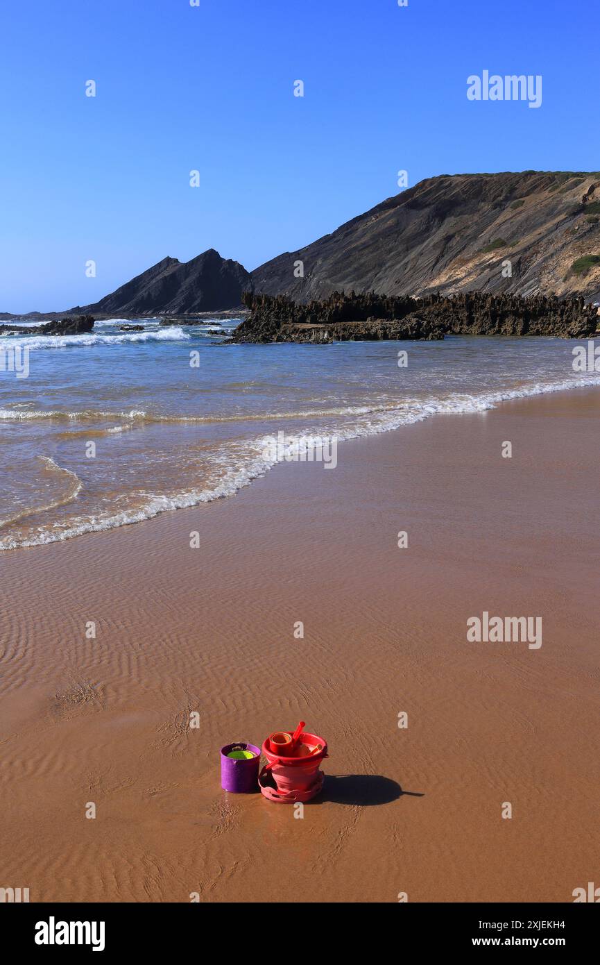 Portogallo, Algarve, Aljezur, Alentejo sud-occidentale e Parco naturale della Costa del Vicentino. Il lavaggio dell'Atlantico sulla spiaggia di Amoreira. Benna e pala in primo piano. Foto Stock