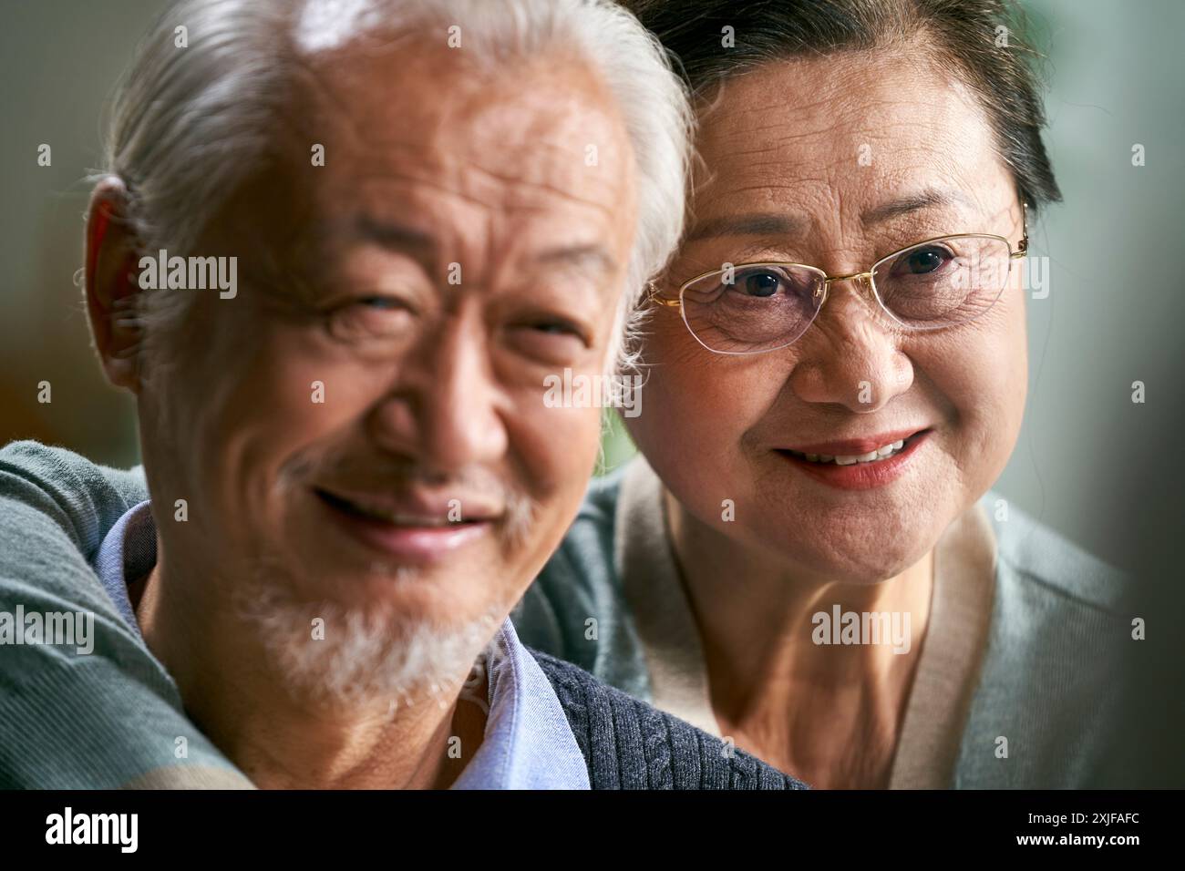 ritratto di una coppia asiatica senior felice e amorevole seduta sul divano a casa Foto Stock