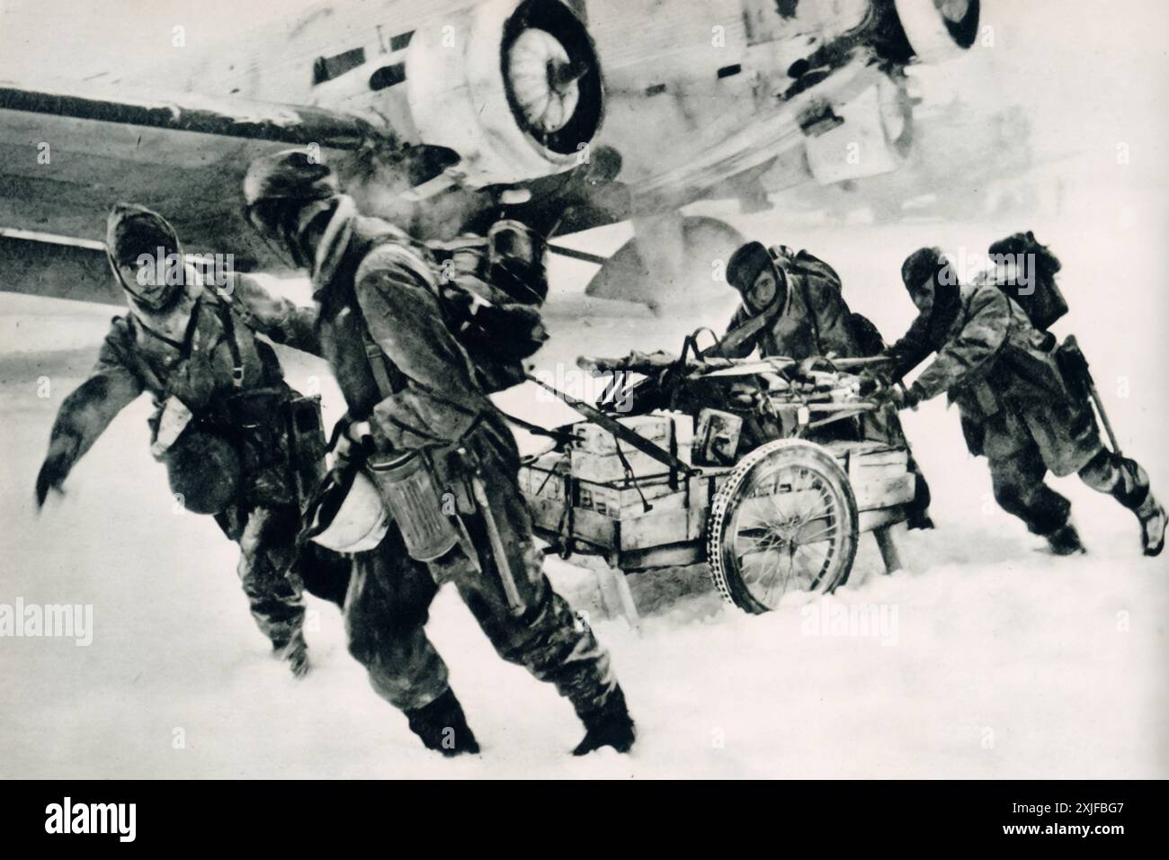 Una fotografia mostra i soldati che trasportano provviste da uno Junkers Ju 52 attraverso una tempesta di neve durante l'operazione Barbarossa nel 1941. Nonostante la tempesta di neve, l'aereo atterrò con successo vicino alle linee del fronte per consegnare un battaglione di tempesta con armi, munizioni e provviste. Foto Stock