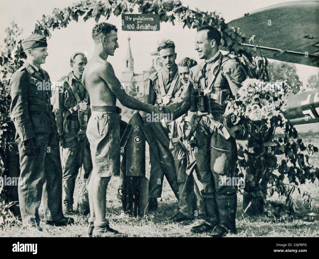 Una fotografia mostra un capo della manutenzione che si congratula con un osservatore aereo per la sua 100a missione di combattimento durante la seconda guerra mondiale. Gli osservatori erano cruciali per raccogliere informazioni e individuare le posizioni nemiche dall'aria. Questa pietra miliare evidenzia il ruolo critico della ricognizione nell'Aeronautica militare tedesca (Luftwaffe) durante l'operazione Barbarossa nel 1941, sostenendo le operazioni di terra sul fronte orientale. Foto Stock