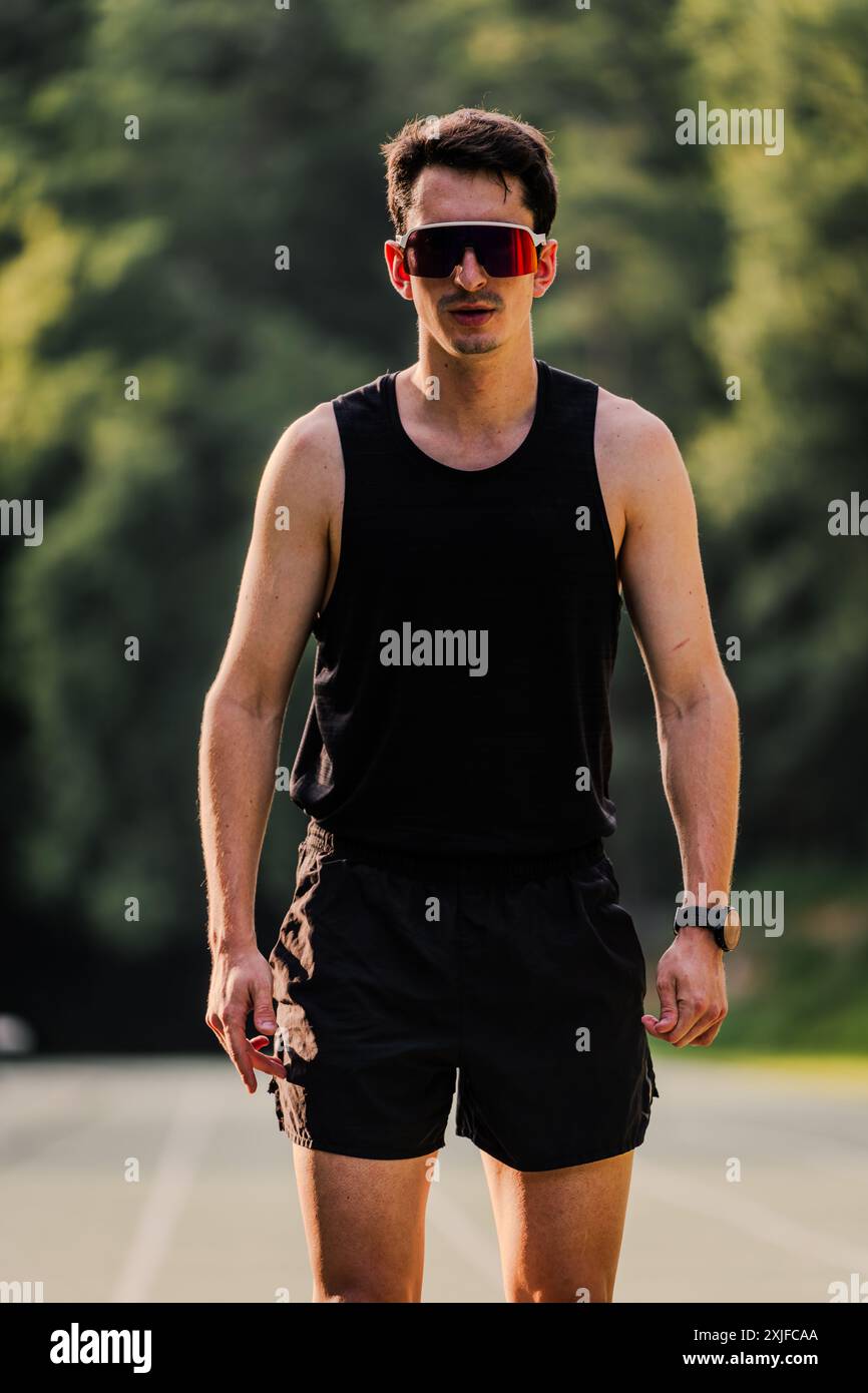 Ritratto di un runner professionista con occhiali da sole e uno sguardo ripugnante. Verticale Foto Stock