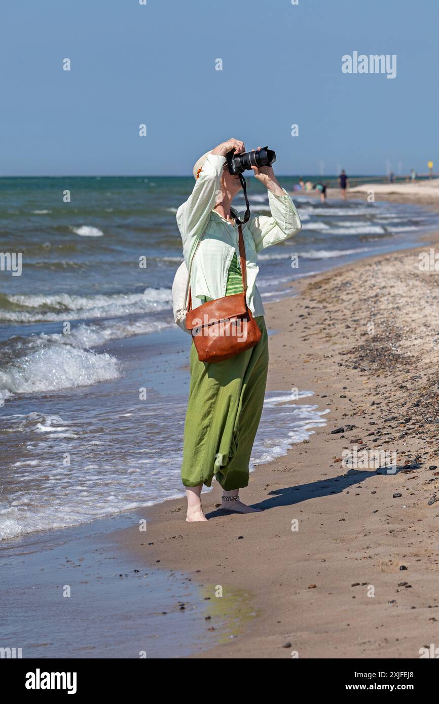 Donna anziana che scatta foto in spiaggia, Darßer Ort, nata a. Darß, Meclemburgo-Pomerania Occidentale, Germania Foto Stock