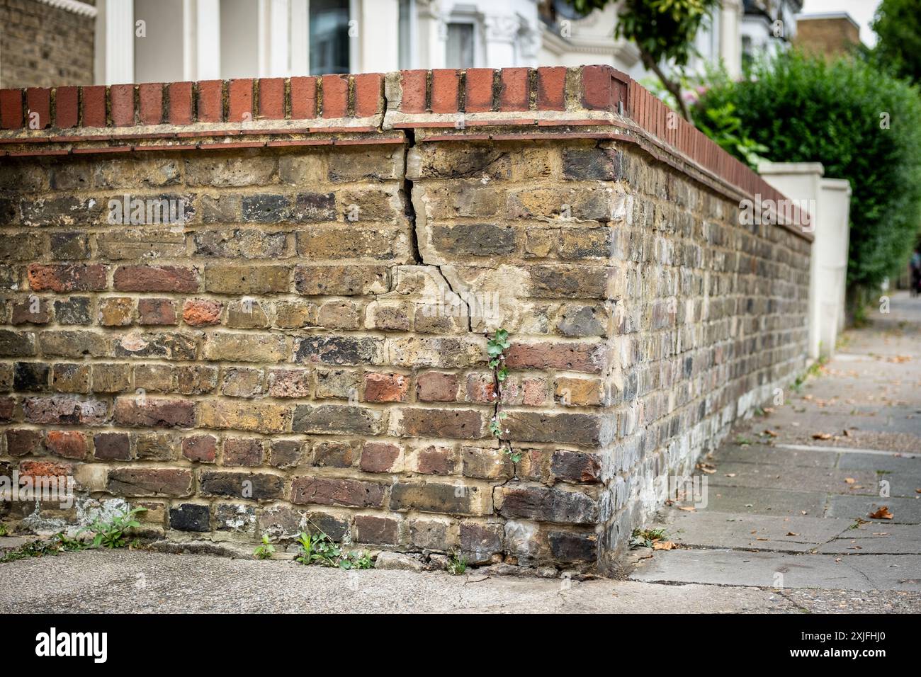 Un muro di mattoni incrinati nella periferia residenziale di British Street Foto Stock