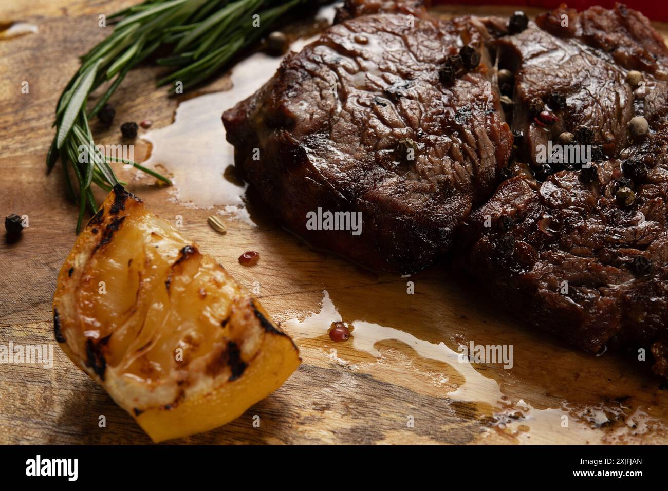 Rib Eye Black Angus alla griglia servito con pepe ed erbe aromatiche su sfondo di legno. Foto Stock