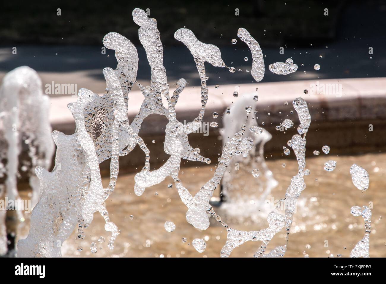 Acqua frizzante dalla fontana del parco cittadino nelle soleggiate giornate estive Foto Stock