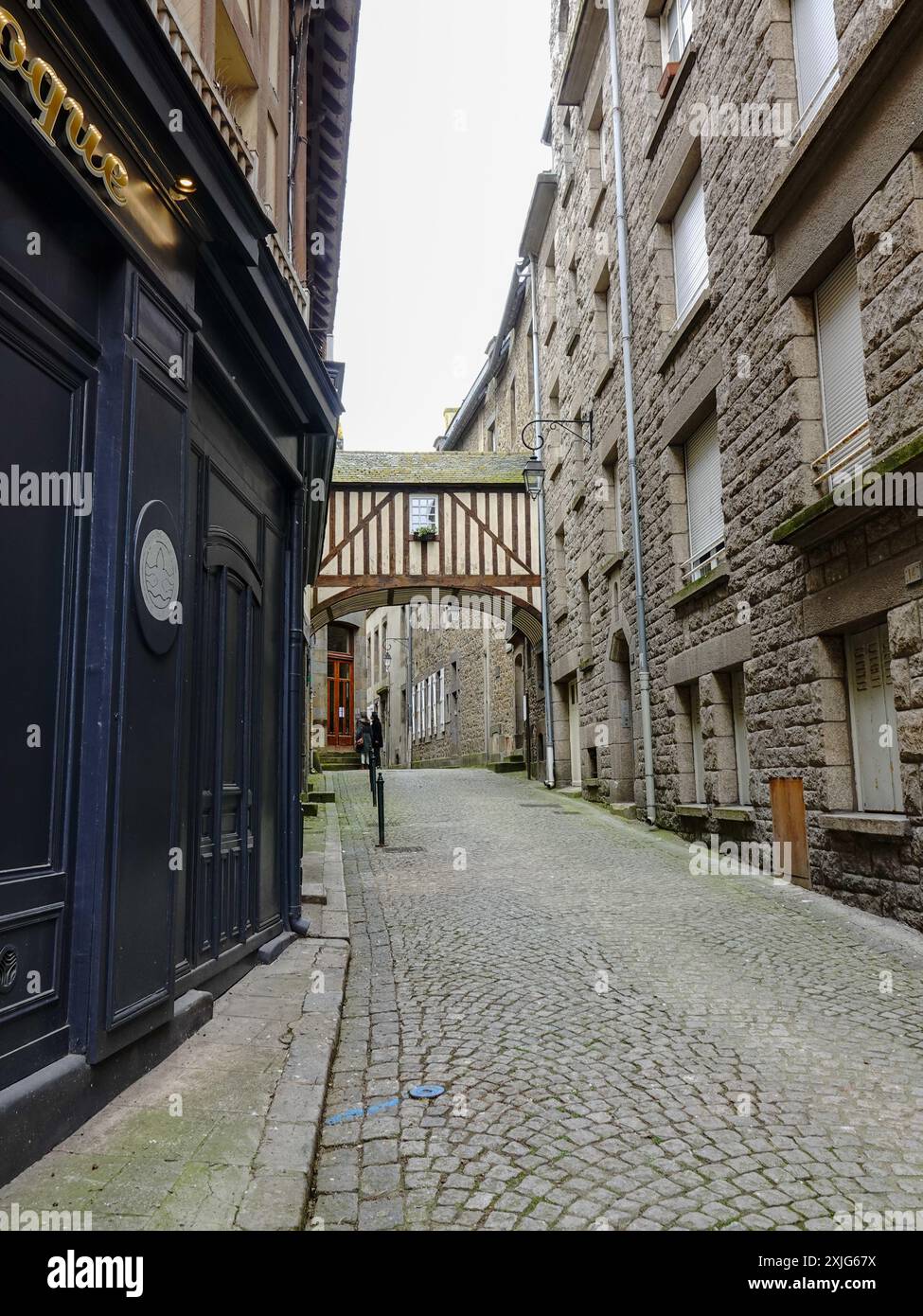 Sopra il passaggio che attraversa la strada, due persone esplorano all'interno delle mura, Intra muros, la città vecchia in rue des Vieux Remparts, Saint-Malo, Francia. Foto Stock