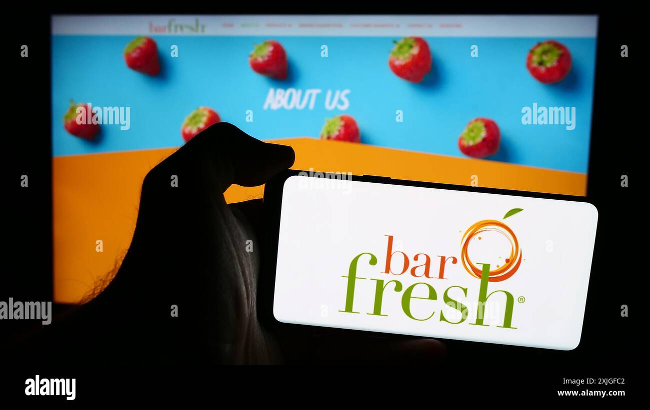 Persona che possiede un telefono cellulare con il logo della società americana di bevande Barfresh Food Group Inc. (BRFH) davanti alla pagina Web. Mettere a fuoco il display del telefono. Foto Stock
