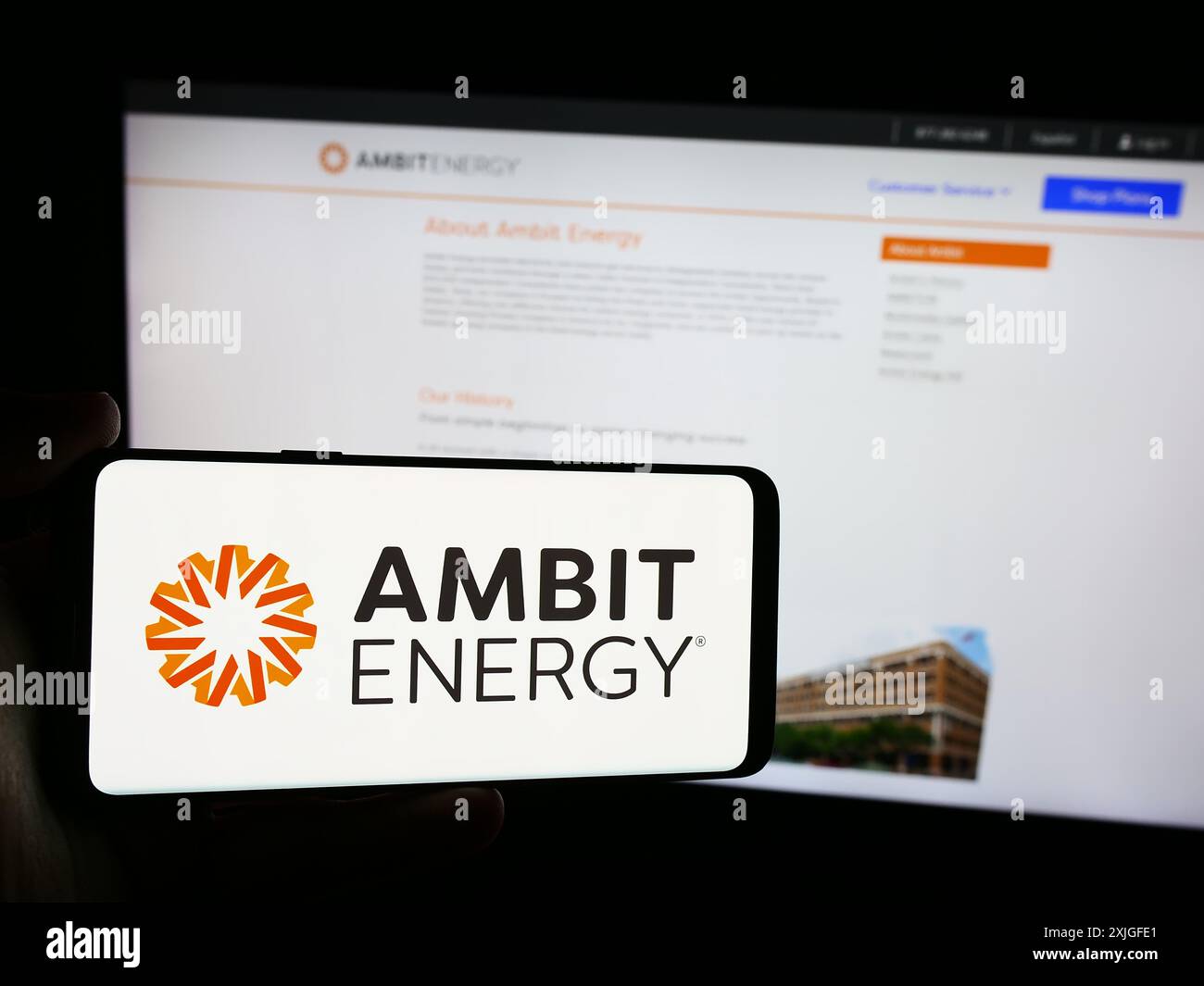 Persona che detiene un cellulare con il logo della società di marketing multilivello statunitense ambit Energy di fronte alla pagina Web aziendale. Mettere a fuoco il display del telefono. Foto Stock