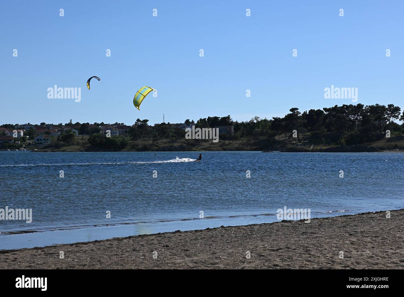 Kitesurfer sta cavalcando un'onda in una giornata di sole con il cielo blu. Foto Stock