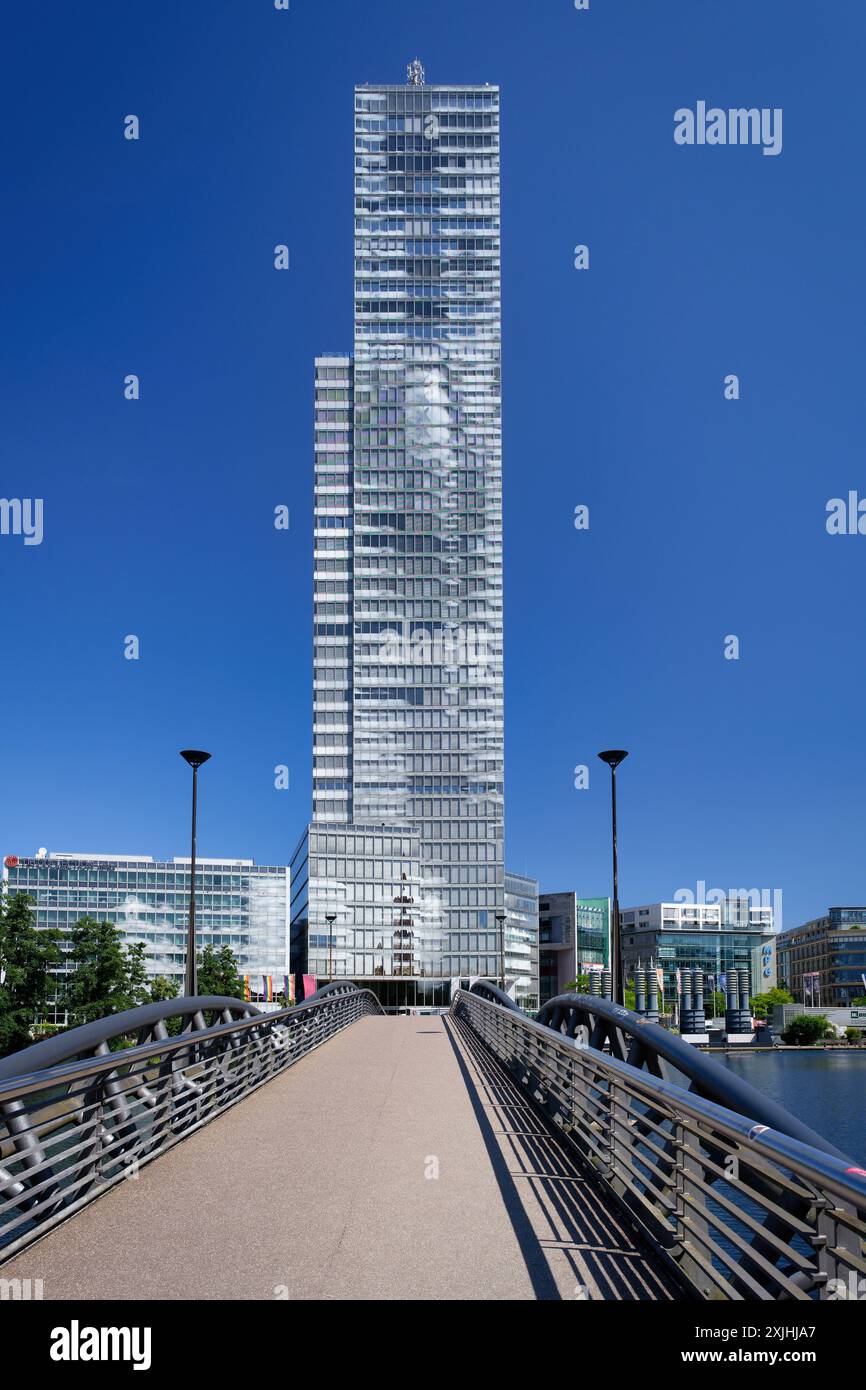 Vista del KoelnTurm attraverso il ponte sul lago MediaPark contro un cielo azzurro Foto Stock