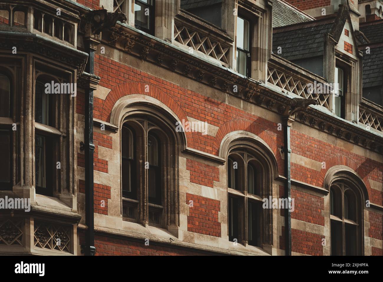 Edificio in mattoni rossi con finestre ad arco e intricati lavori in pietra a Cambridge, Regno Unito. Foto Stock