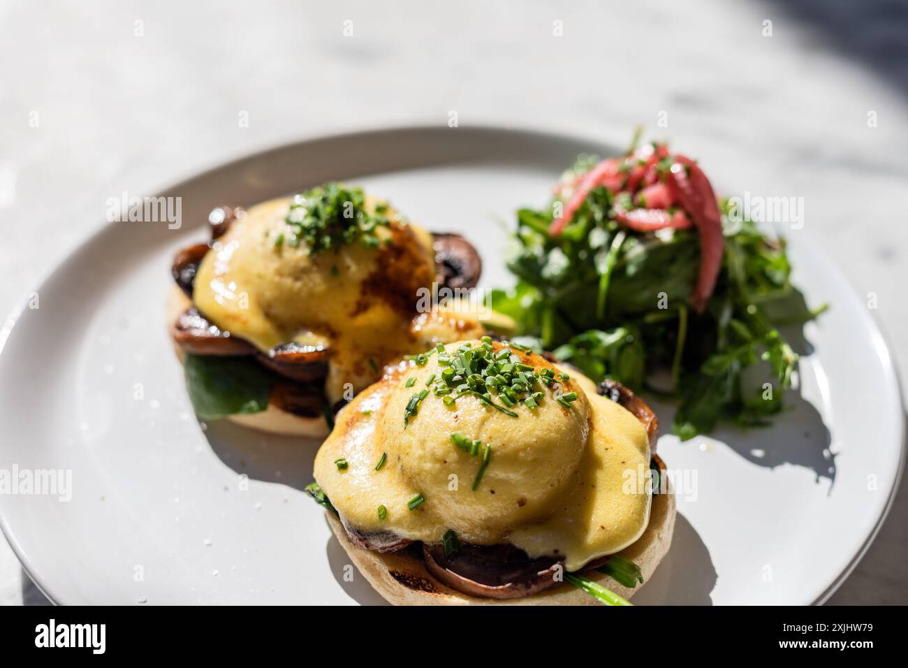 Uova benedict su un muffin con un lato di insalata Foto Stock