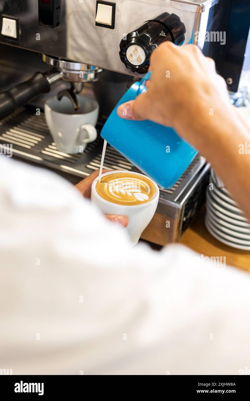 Il latte viene versato in un caffè durante il processo di preparazione. Foto Stock