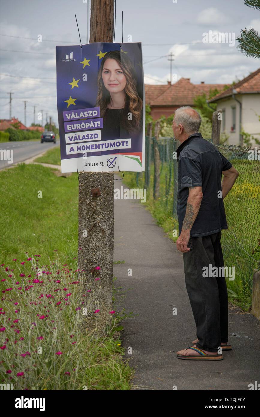 uomo anziano che guarda il manifesto dei candidati alle elezioni europee nel piccolo villaggio ungherese mentre va al seggio elettorale per esprimere il suo voto Foto Stock