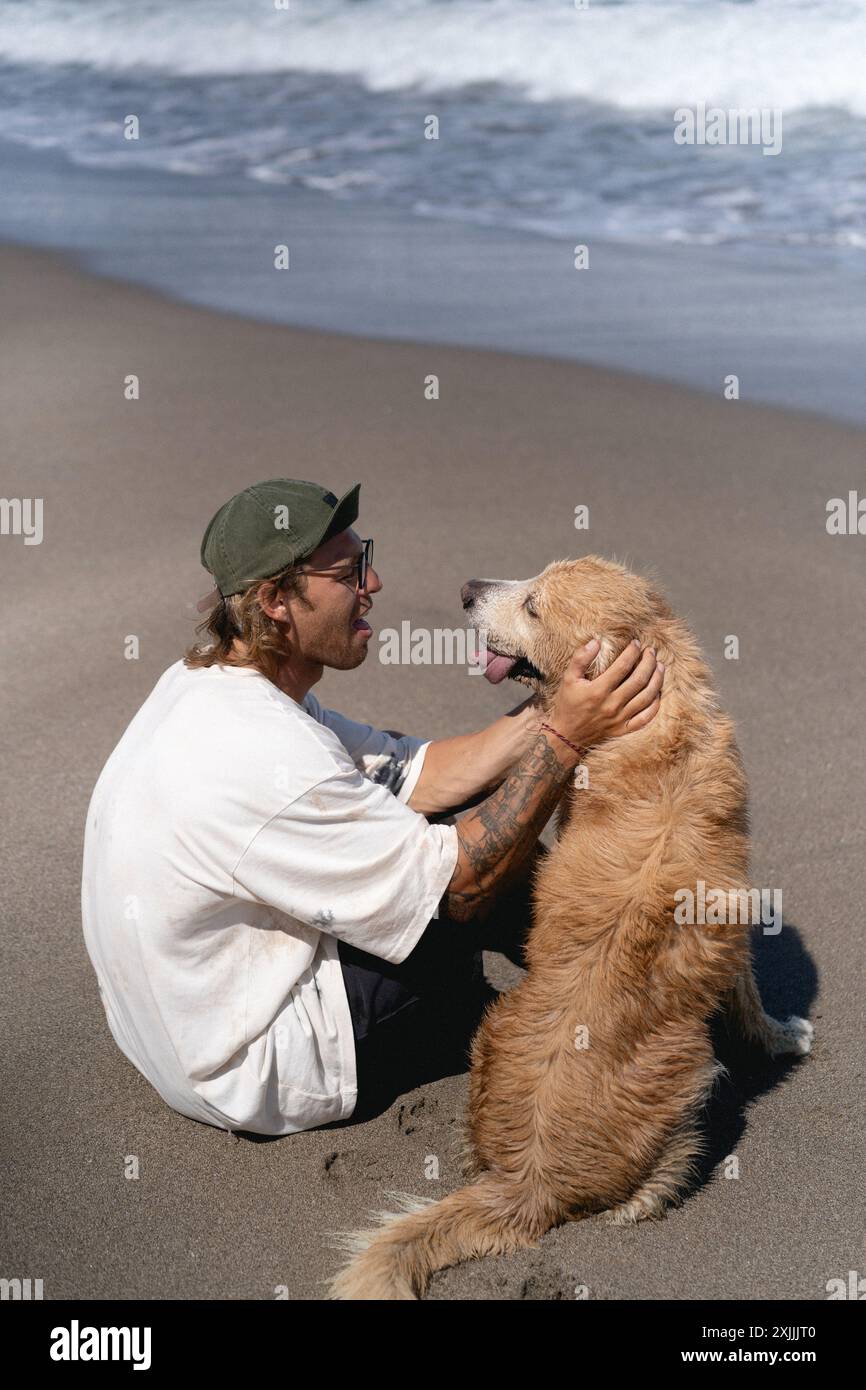 L'uomo gioca sulla spiaggia con il cane retriever. Foto Stock