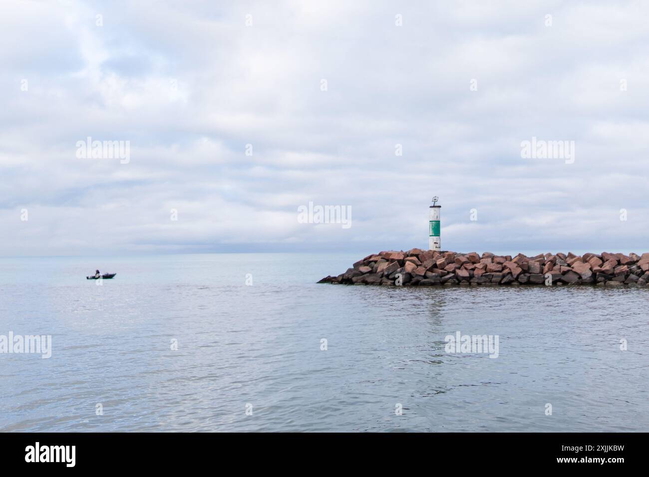 Faro su un molo roccioso a Indiana Dunes con una barca lontana Foto Stock