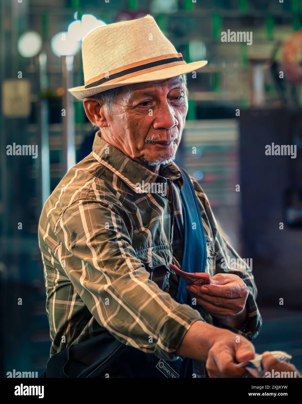 Uomo anziano che indossa un cappello di paglia in un mercato affollato Foto Stock