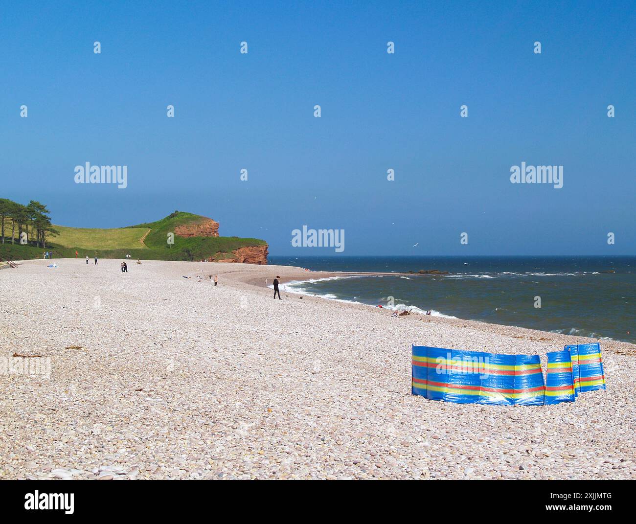 Un flauto colorato fissato nella spiaggia di ciottoli di Budleigh Salterton nell'East Devon. Alla fine della spiaggia si trovano le iconiche scogliere di arenaria rossa Foto Stock