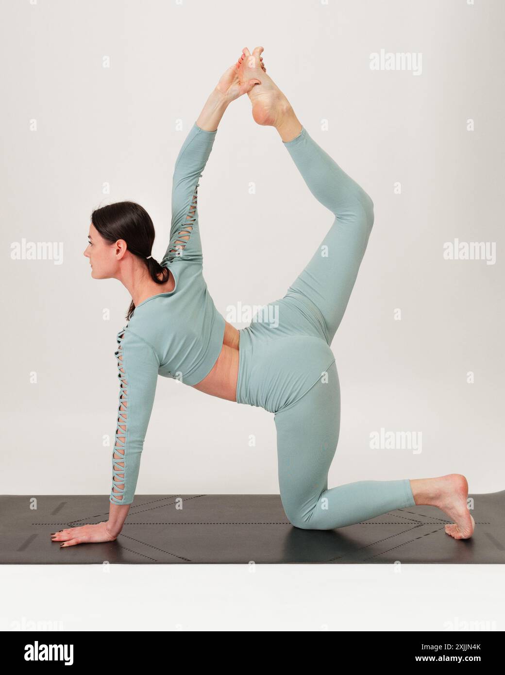 Giovane donna che pratica l'asana su uno studio di sfondo bianco. Foto Stock