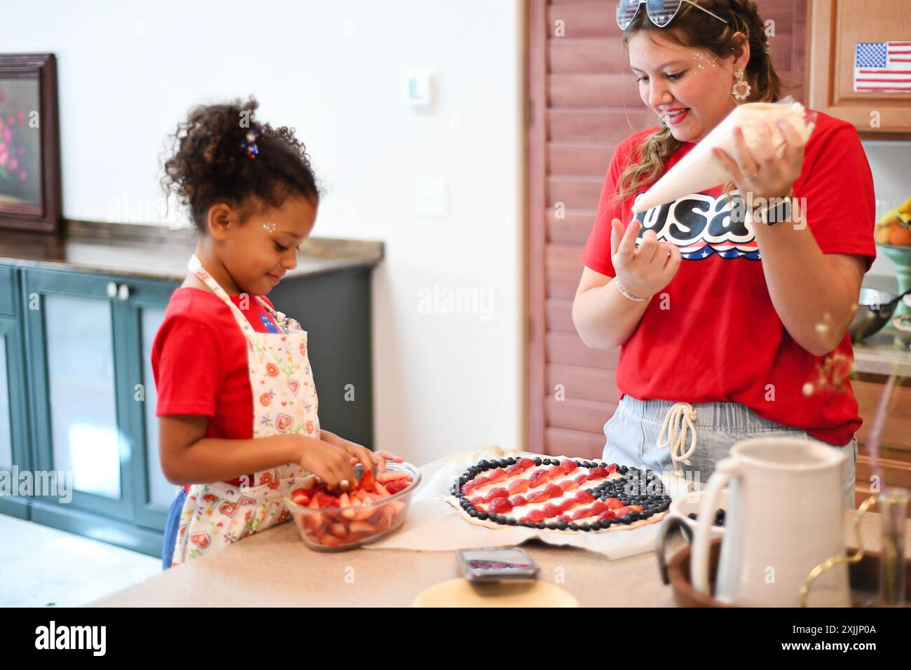 Una donna e un bambino che decorano crostata di frutta in cucina, una stiva Foto Stock