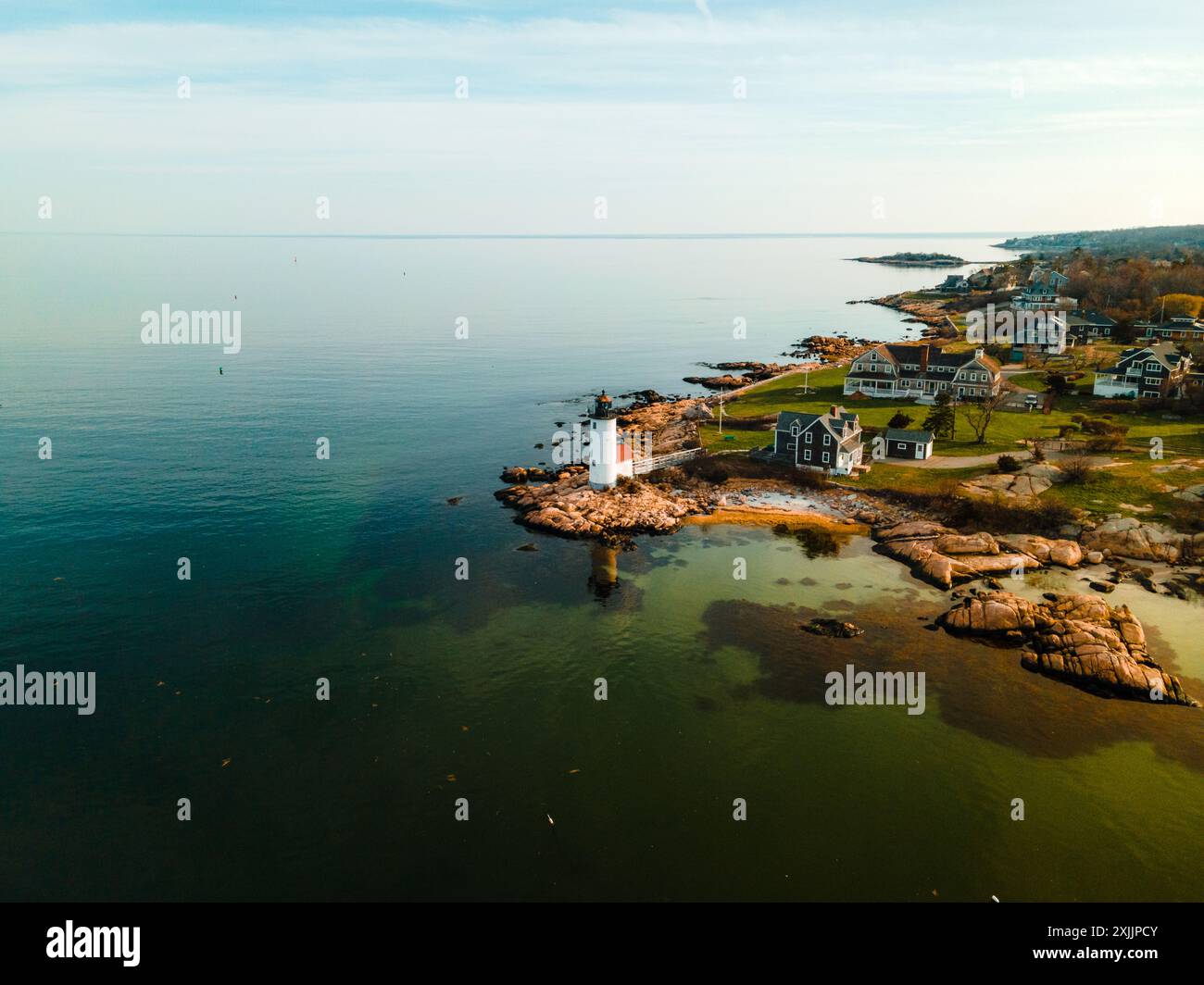 Un piccolo faro protegge la costa rocciosa del New England Foto Stock