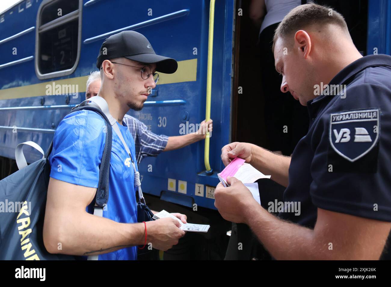 KIEV, UCRAINA - 18 LUGLIO 2024 - Un addetto al treno controlla i documenti dell'atleta Nazar Chepurnyi (L) prima di salire a bordo del treno mentre la squadra di ginnastica artistica Ucraina parte per le Olimpiadi estive di Parigi 2024, Kiev, capitale dell'Ucraina. Foto Stock